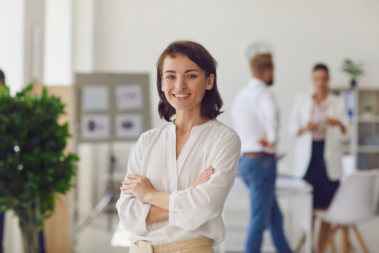 Happy Successful Business Lady or Company Employee Standing in Office Looking at Camera and Smiling