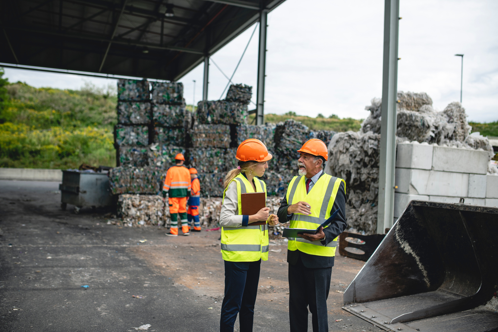 Managers and Workers Outdoors at Waste Management Facility